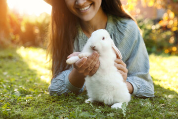 Happy woman with cute rabbit on green grass outdoors, closeup