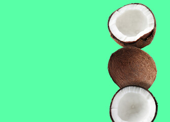 Stack of fresh coconuts on light green background. Space for text