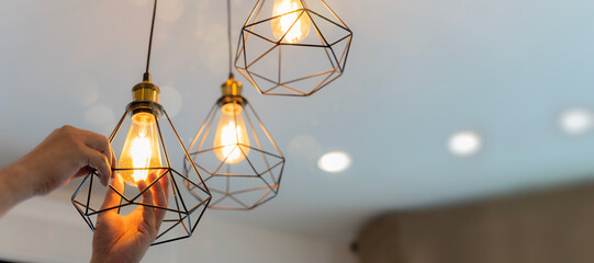 Handyman choosing between energy save and cheap incandescent lamp while changing light in the...