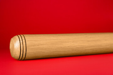 Wooden baseball bat on red background, closeup. Sports equipment