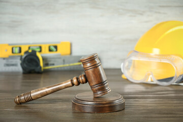 Construction and land law concepts. Judge gavel, protective helmet with safety goggles on wooden table