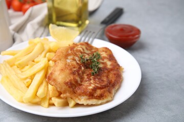 Tasty soda water battered fish, potato chips and lemon slice on light grey table