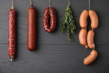 Different delicious sausages and bunch of rosemary hanging near dark grey wooden wall - Powered by Adobe