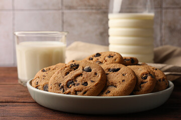 Delicious chocolate chip cookies and milk on wooden table, closeup