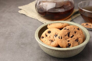 Delicious chocolate chip cookies and tea on grey table. Space for text