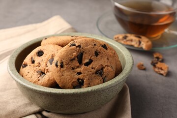 Delicious chocolate chip cookies and tea on grey table, closeup