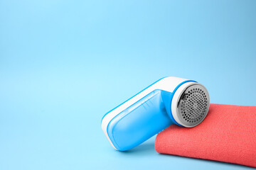 Modern fabric shaver and cloth with lint on light blue background. Space for text