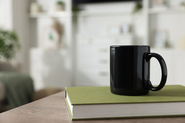 Blank ceramic mug and book on wooden table. Mockup for design