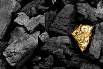 Fototapeta na wymiar Shiny gold nugget on coals, closeup view