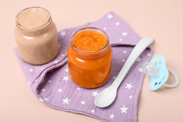 Healthy baby food, spoon and pacifier on pale pink background