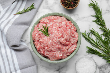 Bowl of raw fresh minced meat with rosemary and spices on white