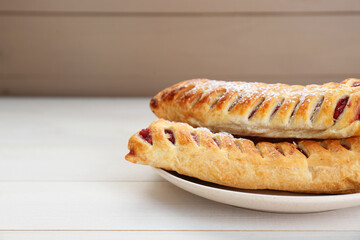 Fresh tasty puff pastry with sugar powder on white wooden table, closeup. Space for text