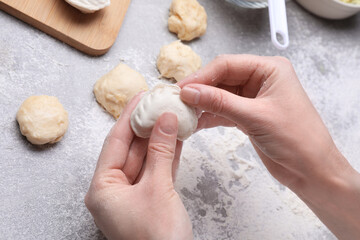 Woman making dumplings (varenyky) at grey table, closeup