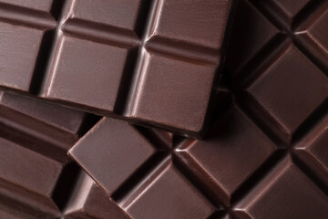 Many delicious dark chocolate bars as background, top view