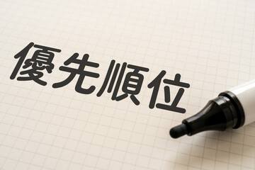 優先順位と書かれたノートとマーカー