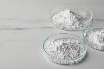 Petri dishes with calcium carbonate powder on white marble table. Space for text