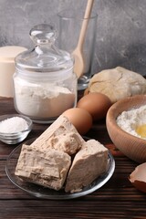 Compressed yeast, flour, salt, dough and eggs on wooden table