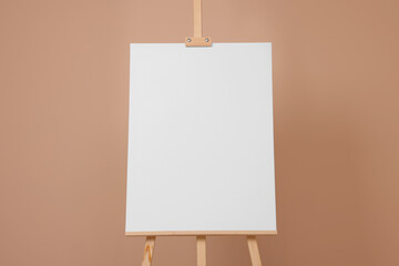 Wooden easel with blank canvas on beige background