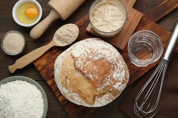 Freshly baked sourdough bread and ingredients on wooden table, flat lay