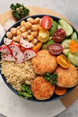 Delicious vegan bowl with chickpeas, cutlets and radish on grey table, top view