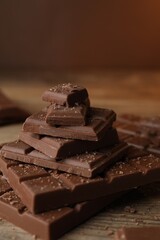 Pieces and crumbs of tasty chocolate on wooden table, closeup