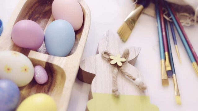 Easter holiday decorations. Easter traditions, painting colorful eggs. Easter Eggs in wooden plate and Spring Flowers on Table. Preparation for Easter.