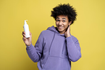 Smiling man holding white bottle of moisturising nourishing anti dandruff shampoo