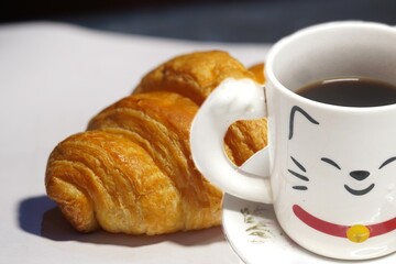 Double Exposure croissants and black coffee in a white cup