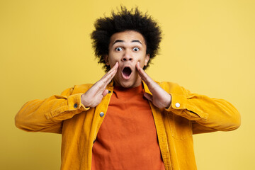 Portrait of young shocked man with open mouth holding hands near face