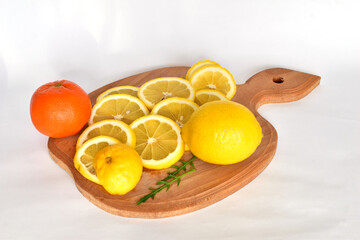 Lemon slices and tangerine lie on a cutting board.