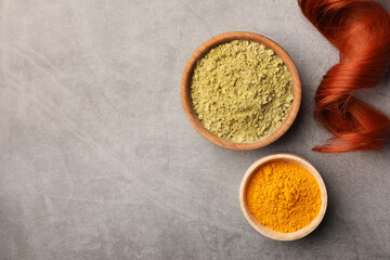 Red strand, henna and turmeric powder on grey table, flat lay with space for text. Natural hair coloring