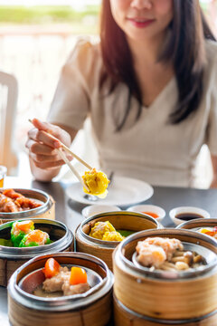 Young woman traveler eating traditional Chinese Dim Sum at restaurant