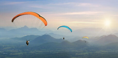 Paragliding in the sky. Paraglider  flying over Landscape sun set Concept of extreme sport, taking adventure challenge.