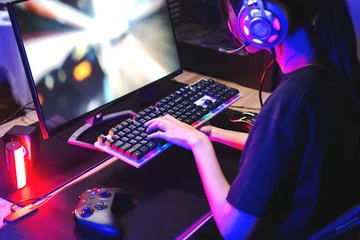 Fotobehang Gaming Happy asia girl gamer wear headphone competition play video game online with computer colorful neon light in living room at night  © joyfotoliakid