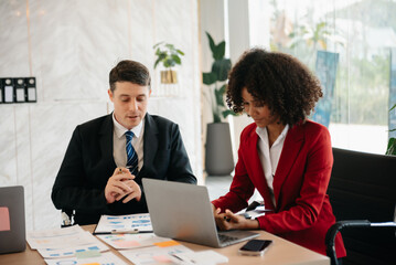 Two business workers talking on the smartphone and using laptop at the office..