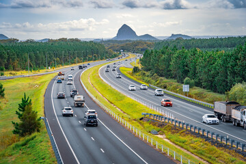 Queensland, Australia - Cars moving along Bruce Hwy with Glass House mountains in the background - obrazy, fototapety, plakaty