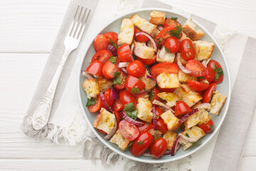 Vegetarian salad of cherry tomatoes, stale bread, onion, olive oil and tomato juice close-up in a plate on the table. Horizontal top view from above