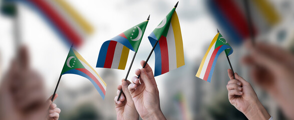 A group of people holding small flags of the Comoros in their hands