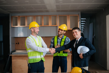 Engineers or architecture shaking hands at construction site for architectural project, holding safety helmet on their hands. successful cooperation concept.