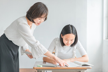 塾・学校で勉強する生徒・子供とわからないところを指導する先生
