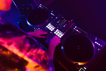 Close up of DJ hands on dj console mixer during concert in the club