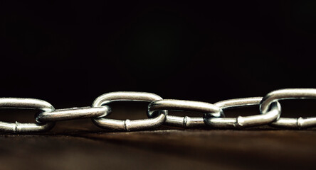 Obraz premium Metal shiny chain on a wooden surface close-up