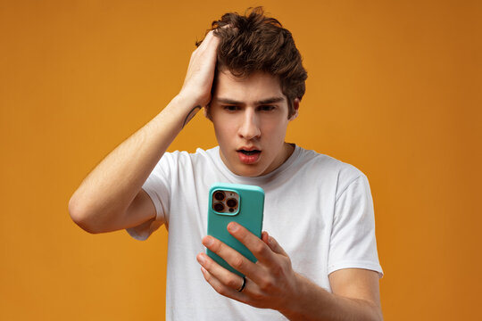 Photo of young guy holding telephone reading bad news on yellow background