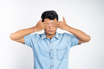 portrait of young Asian man standing with two eyes closed against an isolated background