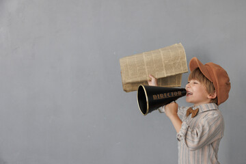 Newsboy shouting against grunge wall background. Boy selling newspaper - 582960716