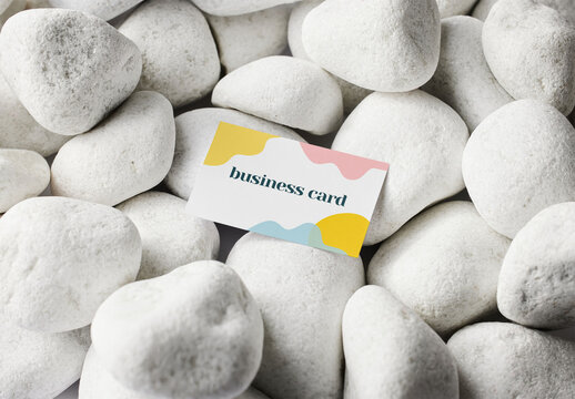 Mockup of customizable horizontal business card design resting on pebbles