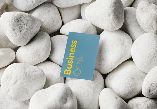 Mockup of customizable vertical color business card design resting on pebbles