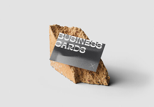 Mockup of customizable horizontal color business card resting against rock available against customizable color background