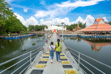 The mother and daughter walking on the bridge to go to the large white Buddha statue reclining on a...
