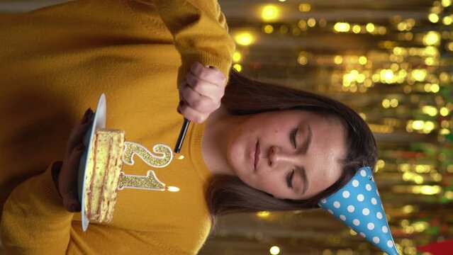 Woman lighting number 21 candles on a birthday cake with lighter. Smiling Girl holding birthday cake and looking at camera at party. POV.